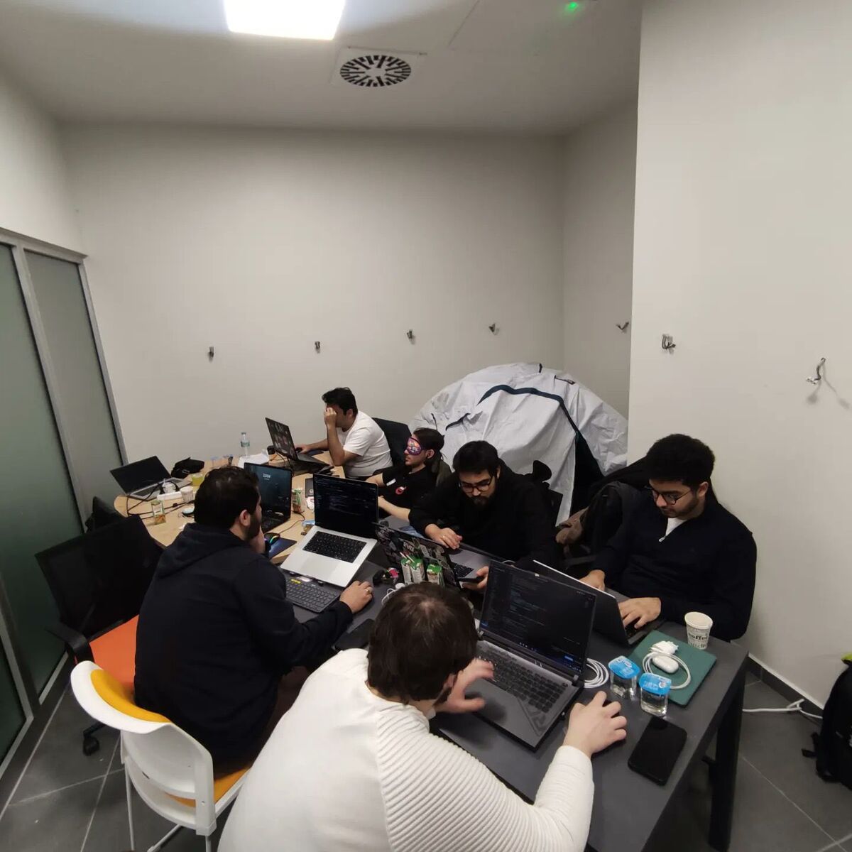 A hackathon working session with laptops around a long table
