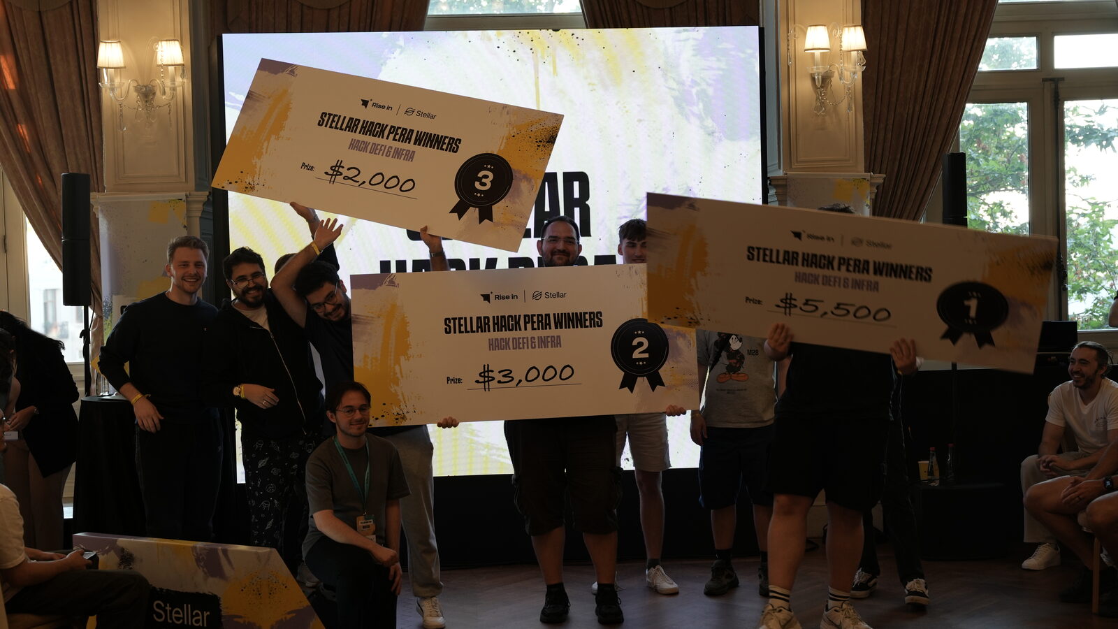 Prize ceremony on stage with oversized cheques for the winning teams